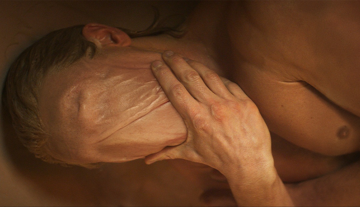 A still from the Clayface trailer showing a man pressing his hand against a smooth, featureless face.